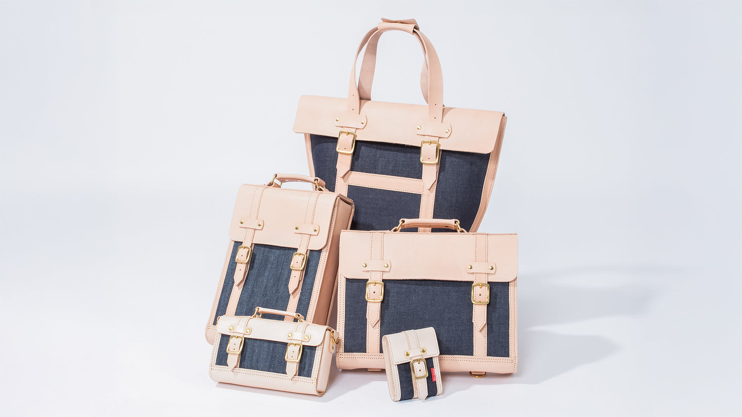 ROAVAN（ローバン） RASWING（ラスウィング）の公式集合写真。栃木レザーの生成りヌメ革、倉敷デニム、真鍮を組み合わせた受注生産の本革バッグと革小物のラインナップ。日本製素材と職人技を活かし、使うほどに艶が増して育つクラフトブランド。